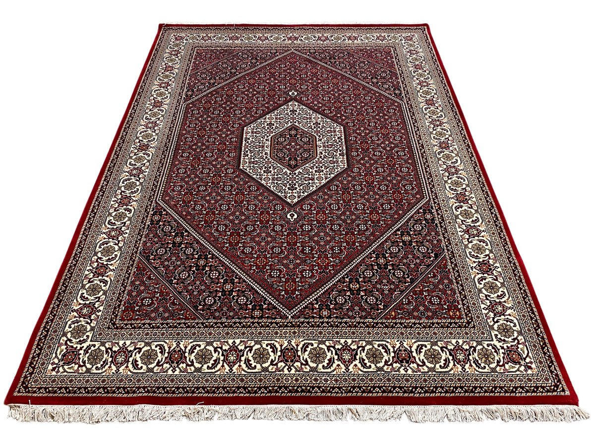 Red carpet with a central medallion, symmetrical ornamentation, and fringes along the edge