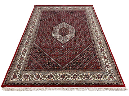 Red carpet with a central medallion, symmetrical ornamentation, and fringes along the edge