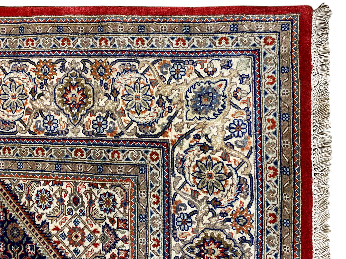 Carpet corner with fringe: light patterned area, red border, and blue-patterned stripes