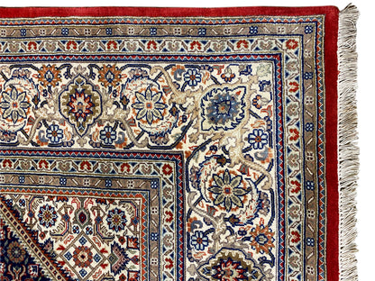 Carpet corner with fringe: light patterned area, red border, and blue-patterned stripes