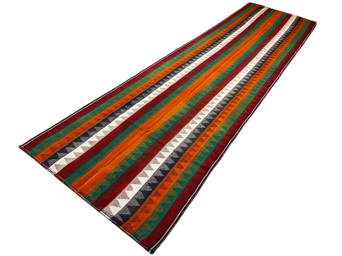Jajim runner rug placed diagonally: multicolored stripes, zigzag pattern, bound edge