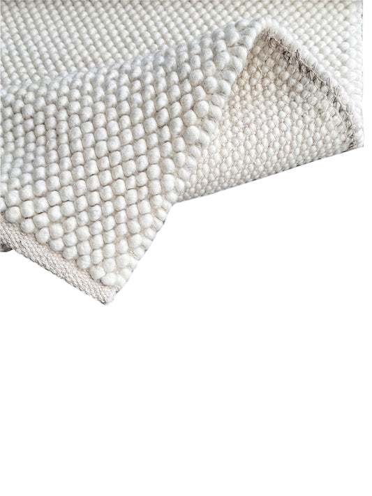 Cream-white loop-pile rug, rectangular edge with a fringed look
