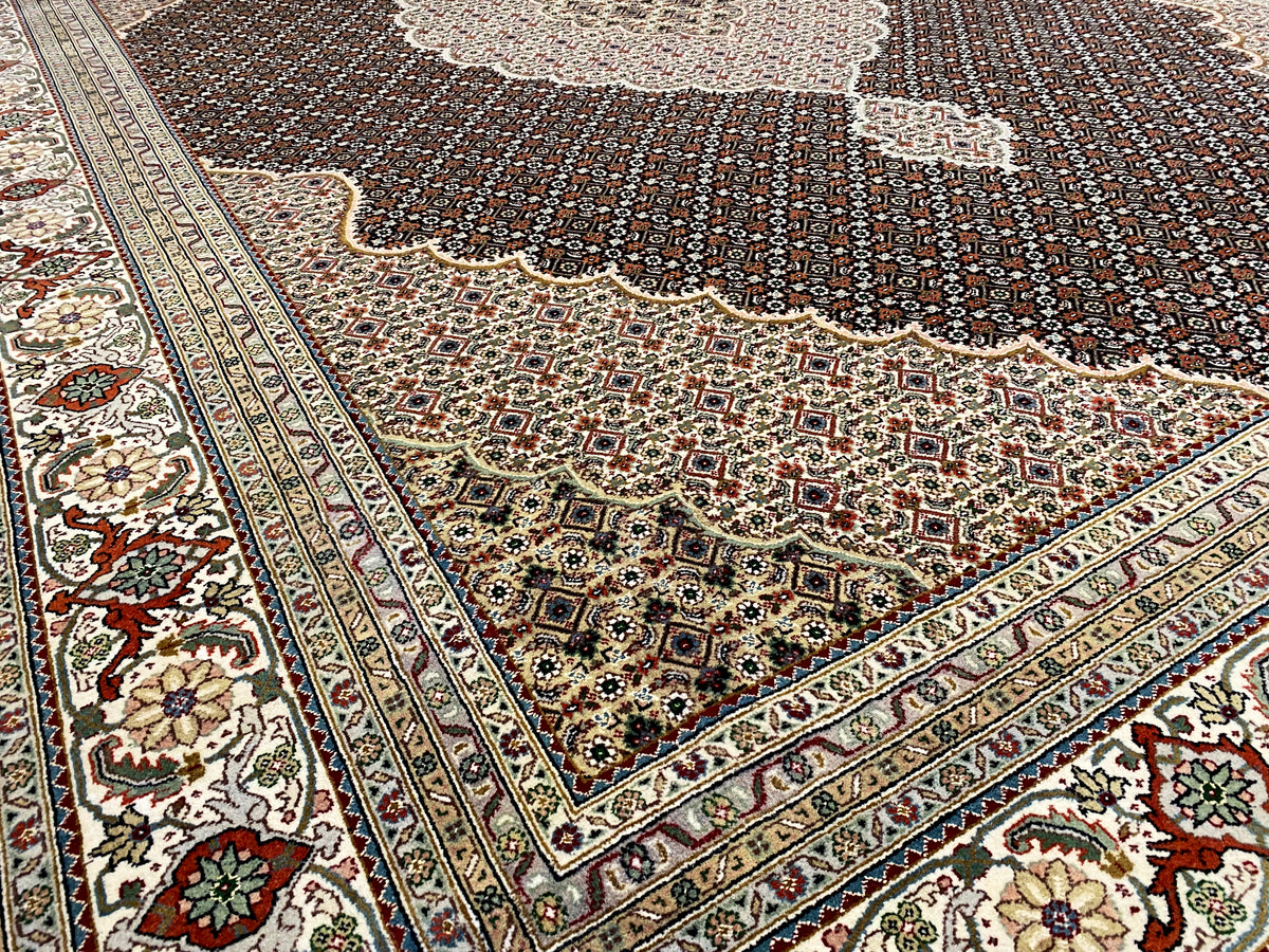 Corner of a dark brown rug with an ornamental border and floral details