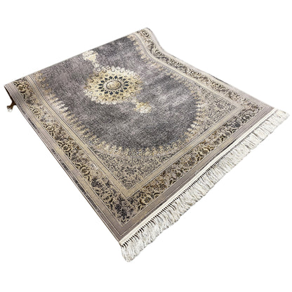 Rug in angled view with medallion, mottled gray, gold lines and fringe