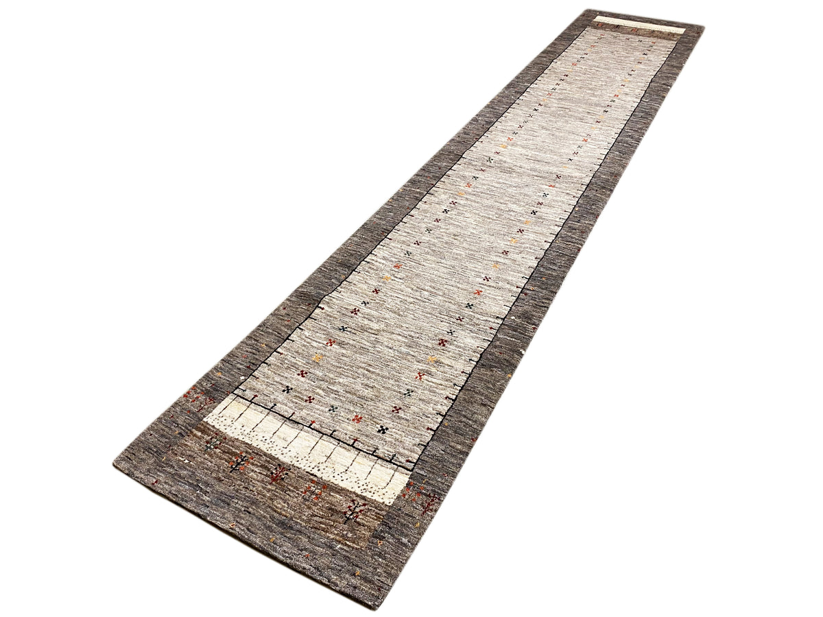 Gabbeh runner rug in a longitudinal view, light beige field with a dark brown side border