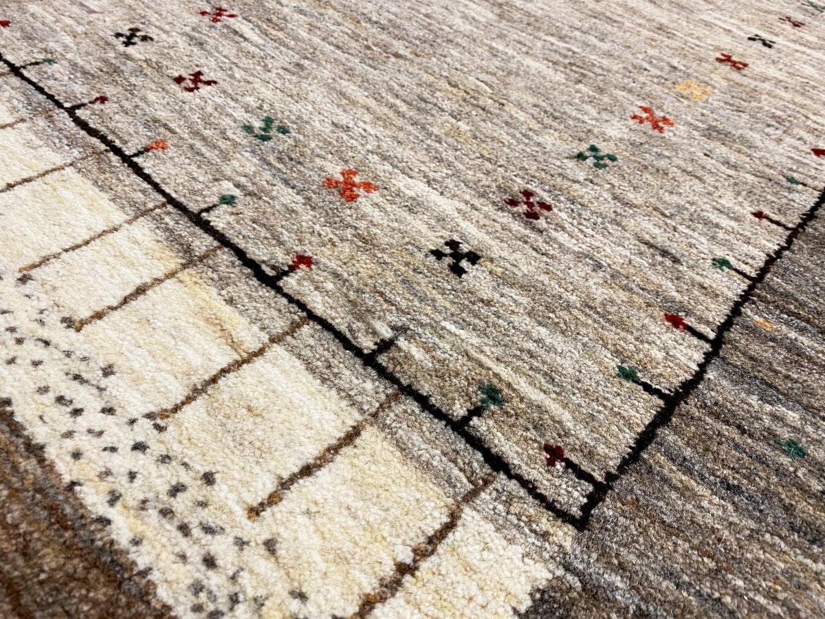 Close-up of a Gabbeh runner: woven lines and color dots in the pattern, light gray