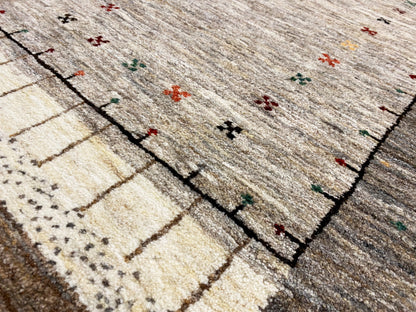 Close-up of a Gabbeh runner: woven lines and color dots in the pattern, light gray