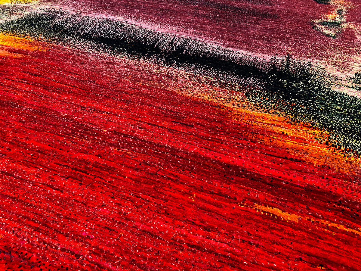 Close-up of a carpet surface with red stripes, a dark pattern, and an orange-yellow gradient