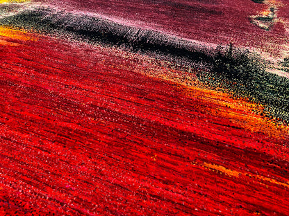 Close-up of a carpet surface with red stripes, a dark pattern, and an orange-yellow gradient