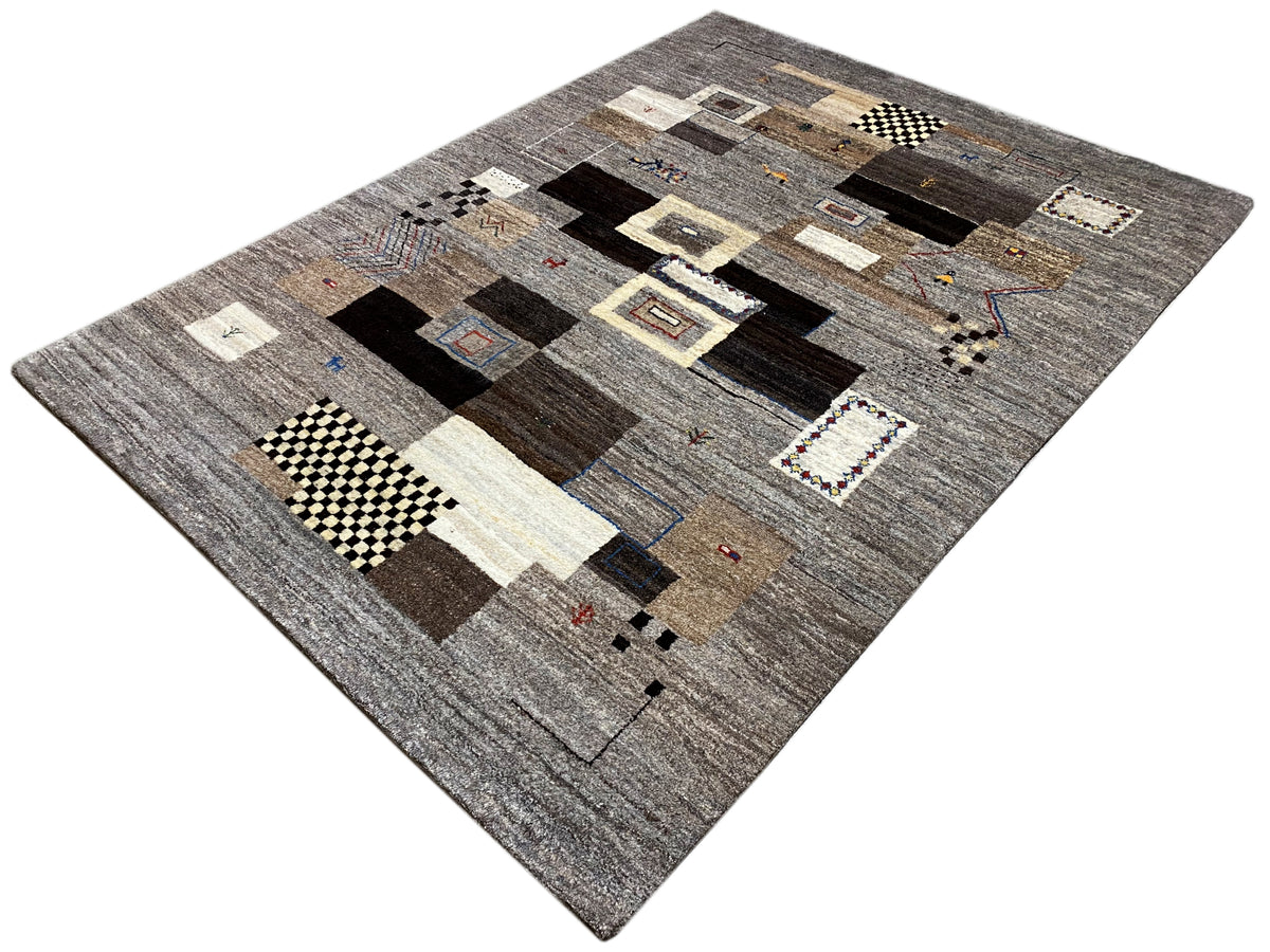 Gabbeh rug 235x171 cm, shown at an angle: patchwork motifs in gray and dark brown