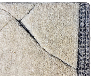 Close-up of the carpet edge: cream-colored pile with blue decorative trim