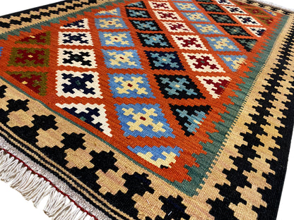 Close-up: kilim rug with colorful diamonds, cross motifs, and fringe along the bottom edge