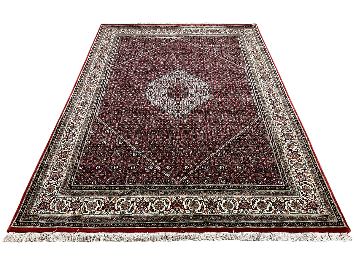 Bidjar rug at an angle: reddish-brown ground pattern with a central medallion and decorative border
