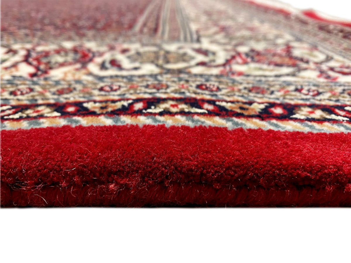 Close-up of the carpet surface: red pile and patterned border along the edge