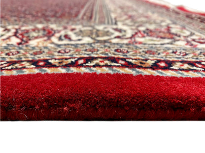 Close-up of the carpet surface: red pile and patterned border along the edge