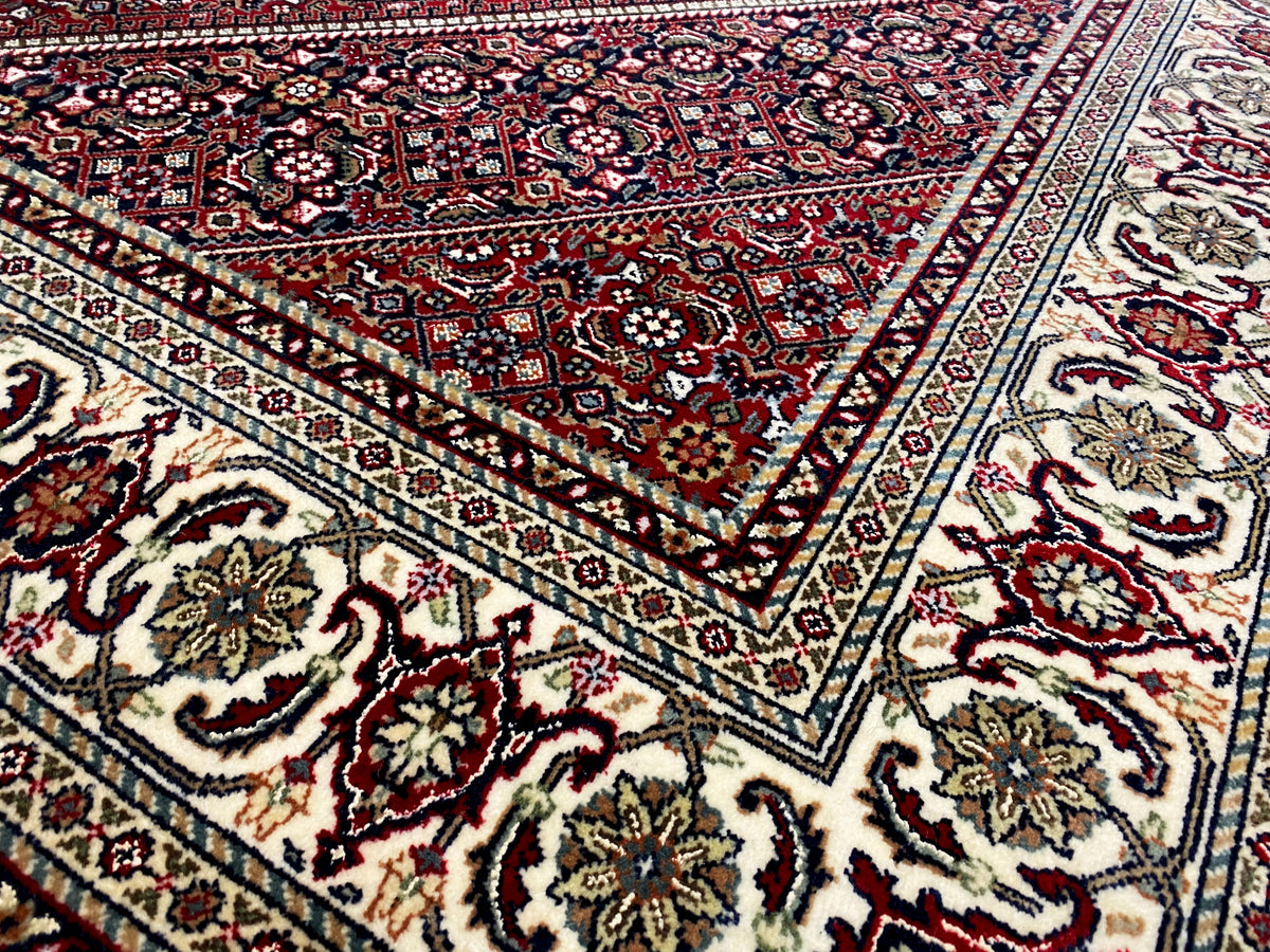 Close-up of the carpet pattern with red ornaments, blue accents, and decorative border