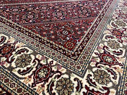 Close-up of the carpet pattern with red ornaments, blue accents, and decorative border