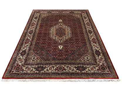 Red Bidjar rug with a central medallion, surrounding ornamental borders, and fringes