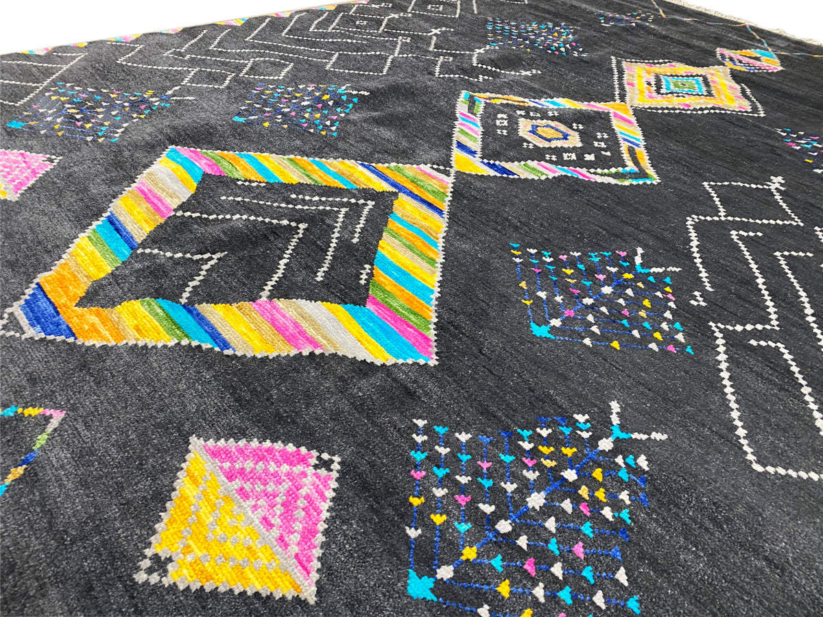 Close-up: black carpet with colorful diamonds, striped borders, and zigzag lines