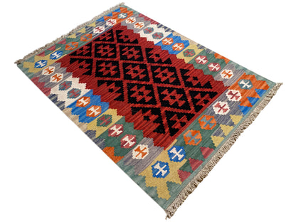Kilim rug in red and black with colorful border motifs and fringes at the corners