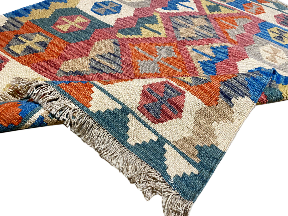 Corner of a Qashqai kilim rug with fringes and colorful geometric motifs