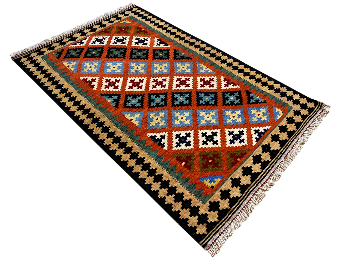 Kilim rug with a central diamond field, black zigzag border, and fringe at the corner