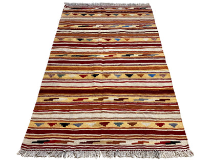 Narrow-oriented kilim rug: multicolored stripes and fringes along the bottom edge