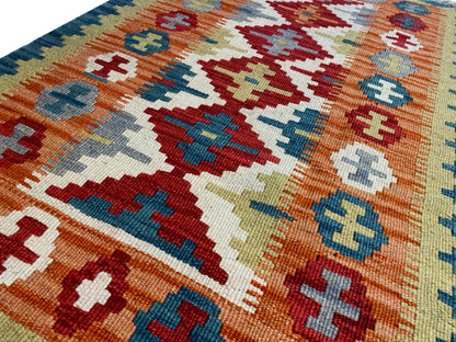Close-up of a kilim rug: Cross and diamond motifs in orange, blue, and cream