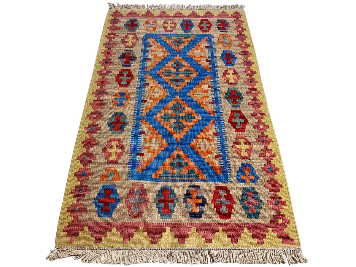 Beige kilim rug with a blue diamond pattern in the center, colorful cross border, and fringe