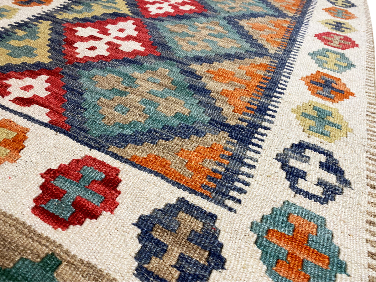 Close-up of a kilim rug: cross and diamond motifs, colorful blocks of color along the edge