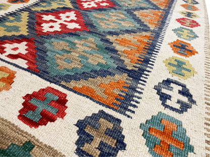 Close-up of a kilim rug: cross and diamond motifs, colorful blocks of color along the edge