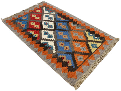 Flatweave rug with geometric pattern, gray background, orange and blue accents, fringes