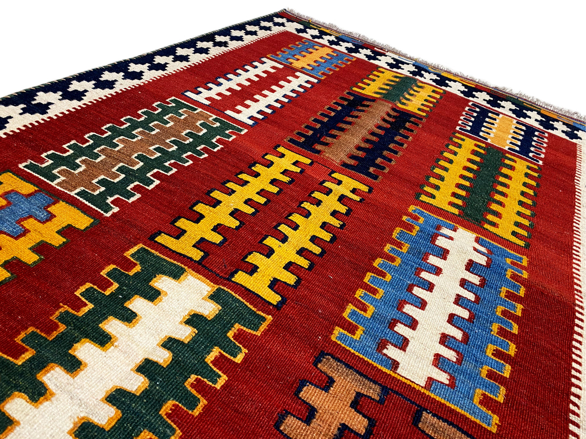 Kilim rug close-up: red field with blue and yellow grids and cross ornaments