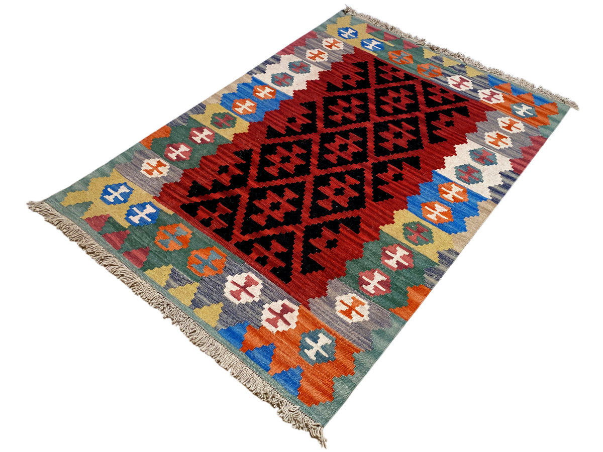 Kilim rug with bold diamond and cross motifs in red, black, blue, and fringes
