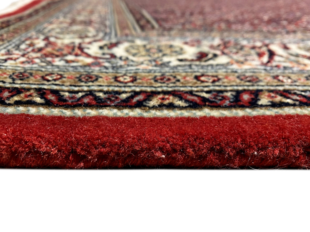 Bidjar rug detail: dense dark red pile at the edge, fine border pattern