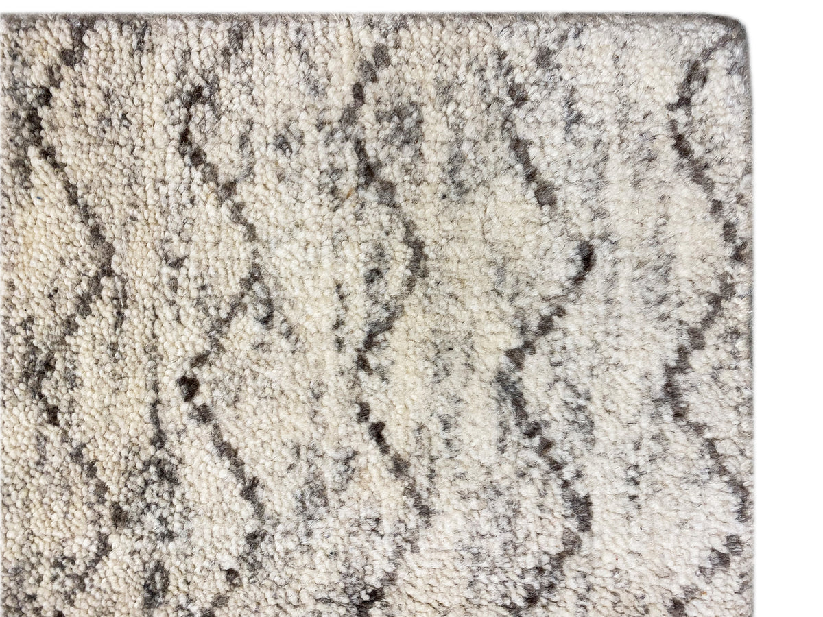 Berber rug close-up: light pile with a gray zigzag pattern and knotted texture