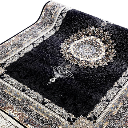 Side view of a black rug: woven decorative border, central medallion, fringe