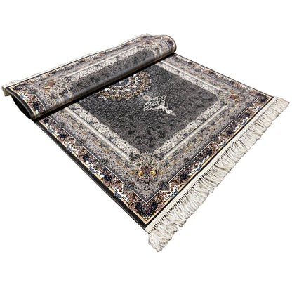 Black oriental rug rolled up on the floor, with a medallion design and fringes