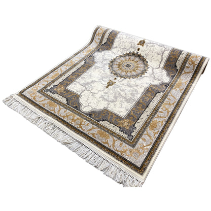 Ornamental cream rug with a round center and gold-colored embellishments, with fringes.