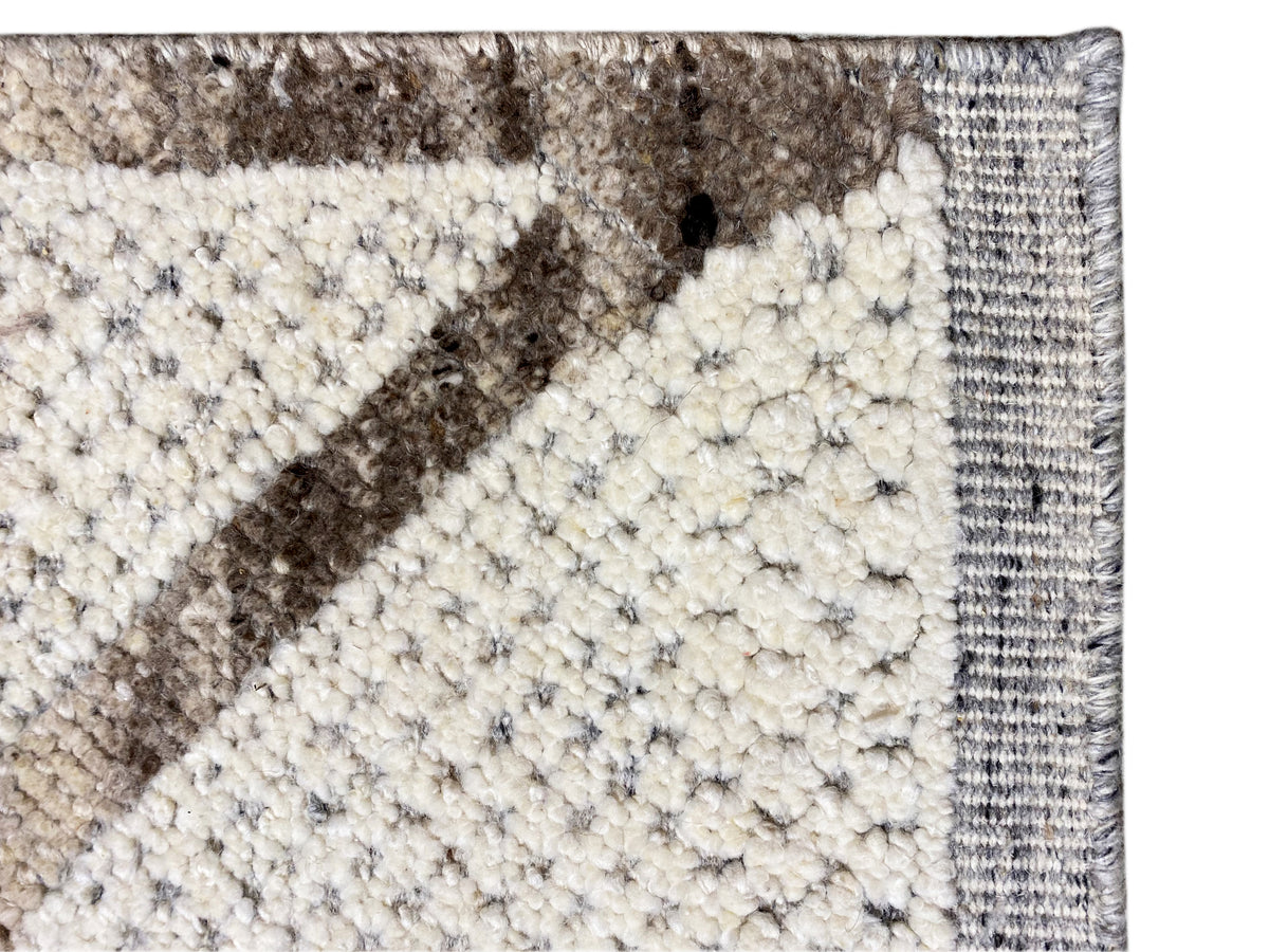 Berber carpet edge and pattern in detail: light pile with a gray stripe