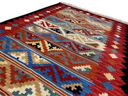 Detailed view of a kilim rug with decorative bars and a mix of patterns in red, blue, and beige.