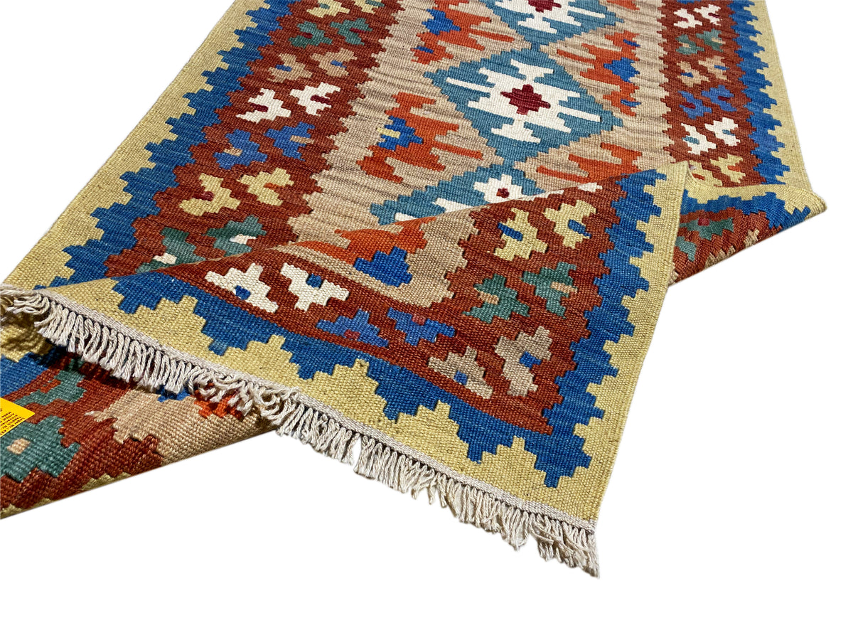 Kilim rug with fringes and colorful cross and diamond patterns in blue, orange, and green