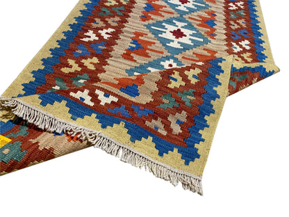 Kilim rug with fringes and colorful cross and diamond patterns in blue, orange, and green