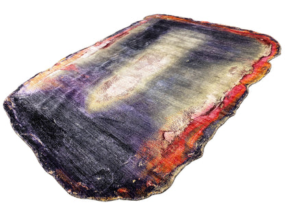 Designer rug appearance: purple-blue with light cream areas and orange accents, irregular edges.