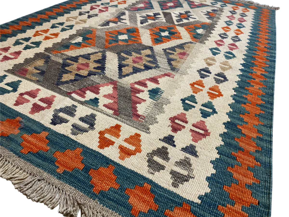Close-up of a kilim rug: cream-colored background with colorful cross and diamond motifs