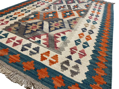 Close-up of a kilim rug: cream-colored background with colorful cross and diamond motifs