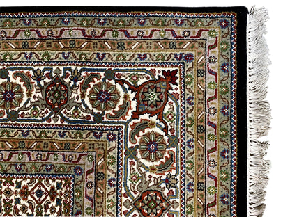 Close-up of the border of a brown Indo-Tabriz rug with floral ornaments and fringes.