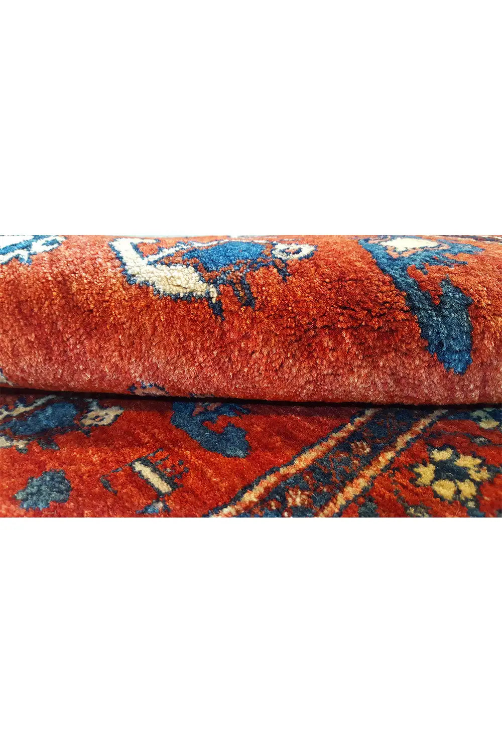 Carpet detail: red pile surface with blue ornaments on a rolled-up carpet