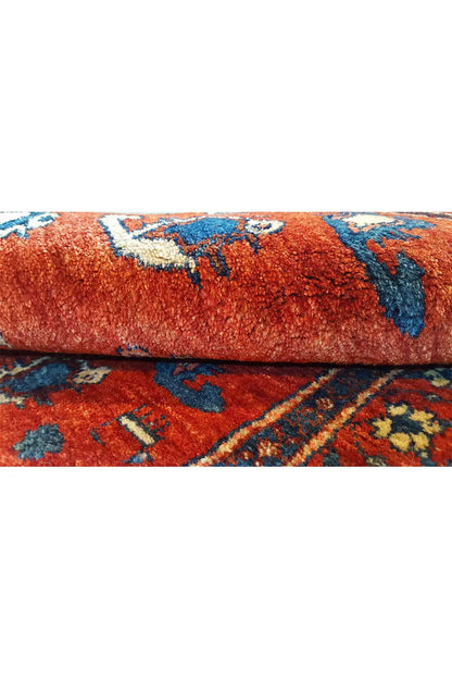Carpet detail: red pile surface with blue ornaments on a rolled-up carpet