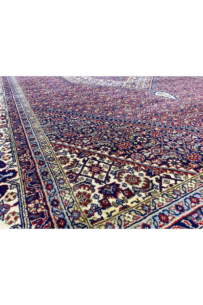 Close-up of Bidjar rug: red floral/geometric pattern in the field with a blue border band